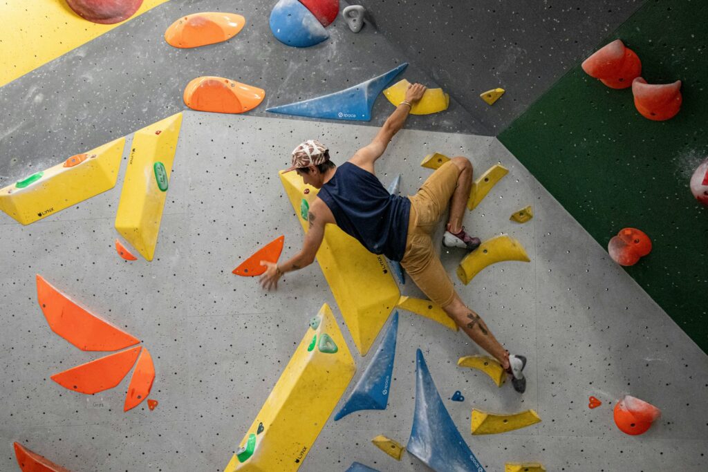 Man climbing a bouldering wall, as in an open bouldering session