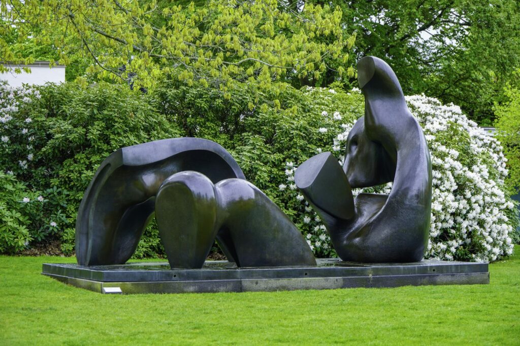 Abstract bronze sculpture displayed on green grass in a garden setting