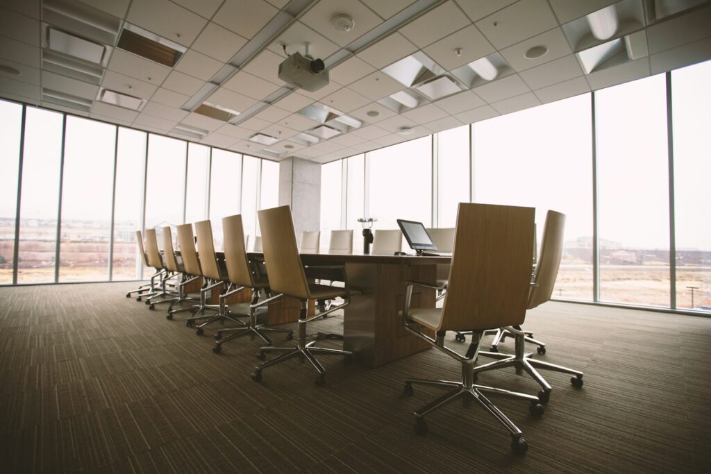 Oval wooden conference table and chairs inside a minimalist boardroom suitable for meeting bookings