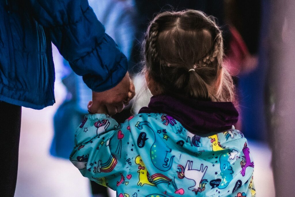 Little girl holding the hand of an adult, illustrating the care at the heart of fostering