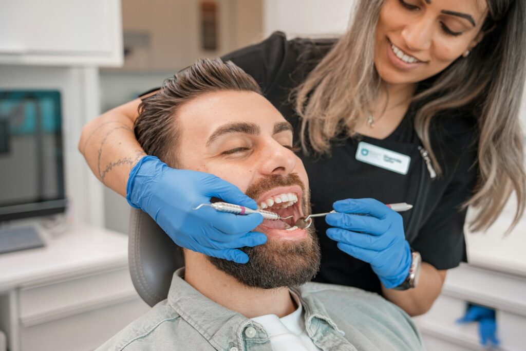 Dentist in blue gloves examining a patient's teeth during a check-up in a dental office